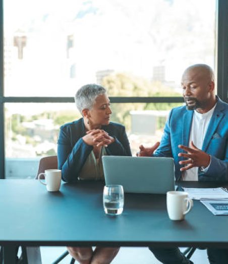 Business, presentation and man on a laptop in a corporate conference or office collaboration with a woman at work. Businessman, manager or coach for marketing, strategy and sales working with CEO.